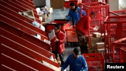 Delivery workers move parcels from an automated sorting belt to carts at a JD.com's smart logistics center on Singles Day shopping festival, in Beijing, China November 11, 2020. REUTERS/Tingshu Wang