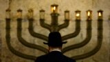 FILE - An Ultra-Orthodox Jewish man stands in front of a menorah on the third eve of Hanukkah, at the Western Wall, Judaism's holiest site in Jerusalem's old city on December 13, 2009. (AP Photo/Sebastian Scheiner, File)