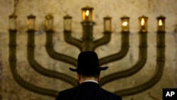 FILE - An Ultra-Orthodox Jewish man stands in front of a menorah on the third eve of Hanukkah, at the Western Wall, Judaism's holiest site in Jerusalem's old city on December 13, 2009. (AP Photo/Sebastian Scheiner, File)