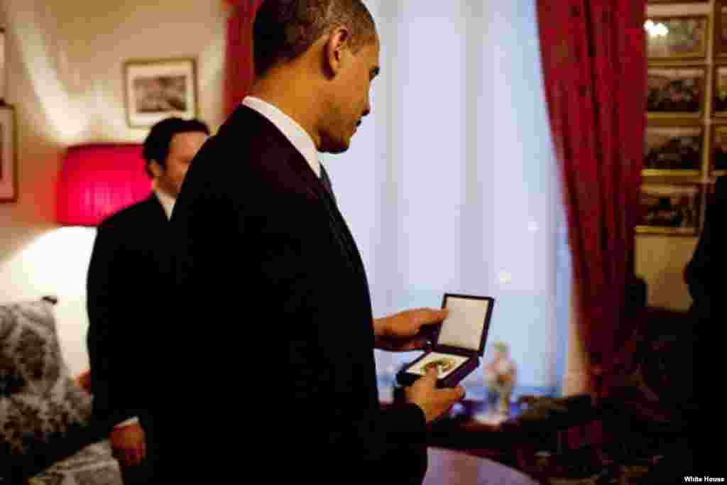 Presiden Barack Obama mengamati medali hadiah Nobel Perdamaian yang diterimanya dari Lembaga Nobel di Oslo, Norwegia (10 Desember 2009).