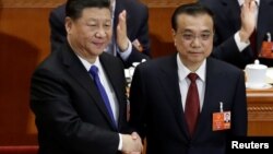 Chinese Premier Li Keqiang, right, shakes hands with Chinese President Xi Jinping, after he is re-elected premier for another term, at the sixth plenary session of the National People's Congress at the Great Hall of the People in Beijing, March 18, 2018. 