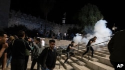 Palestinians react to stun grenades fired by Israeli police to clear the Damascus Gate to the Old City of Jerusalem after clashes at the Al-Aqsa Mosque compound, May 7, 2021.