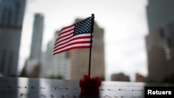 Sebuah bendera Amerika dan mawar merah di tepi selatan kolam refleksi 9/11 Memorial & Museum, menjelang peringatan 20 tahun serangan 9/11 di Manhattan, New York, AS, 8 September 2021. (REUTERS/Mike Segar)