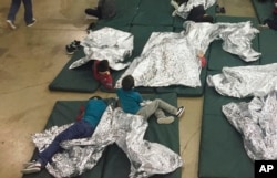 In this photo provided by U.S. Customs and Border Protection, people who've been taken into custody related to cases of illegal entry into the United States, rest in one of the cages at a facility in McAllen, Texas.