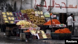 File - A vendor stands next to his fruit stall as he waits for customers near a mosque in Cairo.