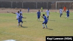 Les équipes d'Athleta FC (blanc) et le club "les amis du monde" (bleu) se rencontrent à Lomé, au Togo, le 18 mars 2017. (VOA/Kayi Lawson)