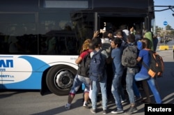 Migrants try to get on a bus following their arrival onboard the Eleftherios Venizelos passenger ship at the port of Piraeus near Athens, Greece, Aug. 29, 2015.