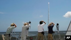 FILE - Photographers track an Atlas V rocket with the Juno spacecraft as it lifts off from Space Launch Complex-41 in Cape Canaveral, Florida, Aug. 5, 2011.