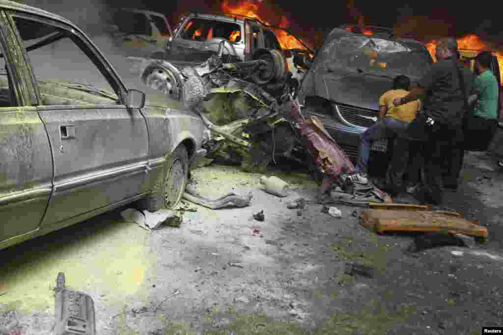 Men gather near burning cars at the site of an explosion in Beirut's southern suburbs, July 9, 2013.