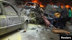 Men gather near burning cars at the site of an explosion in Beirut's southern suburbs, July 9, 2013.