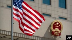 FILE - The American flag flies near the national emblem of China outside of the Bayi Building in Beijing, June 27, 2018. 