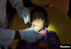 Seorang dokter memeriksa gigi geligi anak laki-laki berusia 7 tahun di sebuah rumah sakit di Chennai, India, 2 Agustus 2019. (Foto: Reuters)