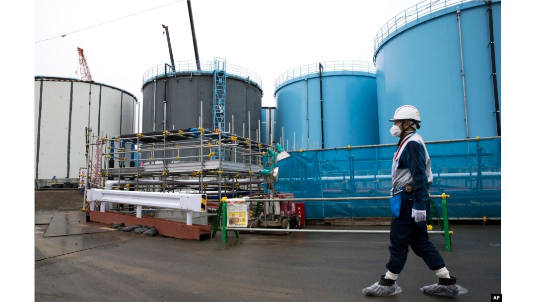 Employee walks past storage tanks for contaminated water at the tsunami-crippled Fukushima Dai-ichi nuclear power plant of the Tokyo Electric Power Co. in Okuma town, Fukushima prefecture, Japan, Feb. 23, 2017.