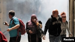 People walk away from tear gas smoke during clashes between Palestinians and Israeli security forces inside the old city of Jerusalem October 30, 2014. Israeli police on Thursday shot dead a 32-year-old Palestinian man suspected of having tried hours earl