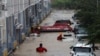 Petugas penyelamat mencari korban atau warga yang membutuhkan bantuan di dekat kendaraan di tempat parkir, bagian bawah bangunan apartemen yang tergenang banjir akibat hujan lebat di kota Daejeon, Korea Selatan (foto: dok). 