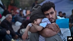 FILE - A Syrian refugee child sleeps on his father's arms while waiting at a resting point to board a bus, after arriving on a dinghy from the Turkish coast to the northeastern Greek island of Lesbos, Oct. 4 , 2015.