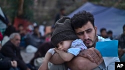 A Syrian refugee child sleeps on his father's arms while waiting at a resting point to board a bus, after arriving on a dinghy from the Turkish coast to the northeastern Greek island of Lesbos, Oct. 4 , 2015.