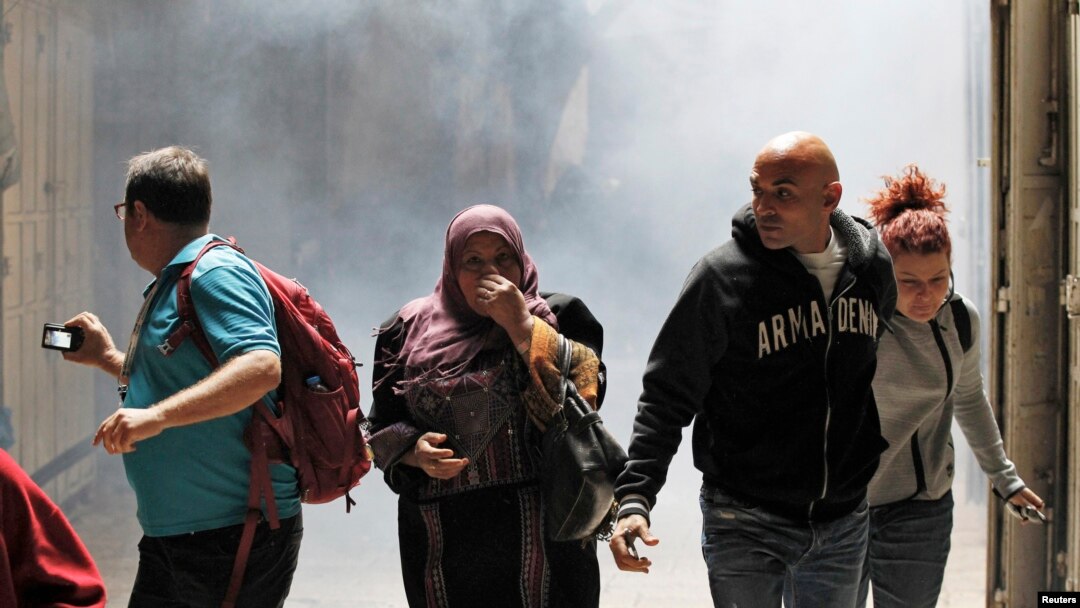 People walk away from tear gas smoke during clashes between Palestinians and Israeli security forces inside the old city of Jerusalem October 30, 2014. Israeli police on Thursday shot dead a 32-year-old Palestinian man suspected of having tried hours earl