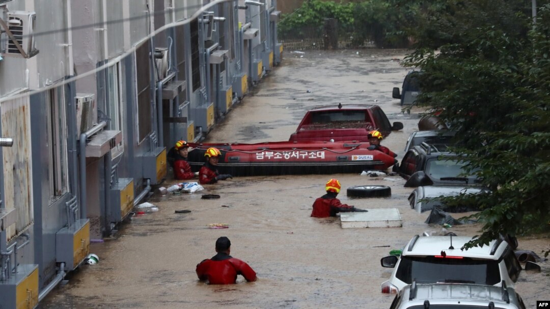 Petugas penyelamat mencari korban atau warga yang membutuhkan bantuan di dekat kendaraan di tempat parkir, bagian bawah bangunan apartemen yang tergenang banjir akibat hujan lebat di kota Daejeon, Korea Selatan (foto: dok). 