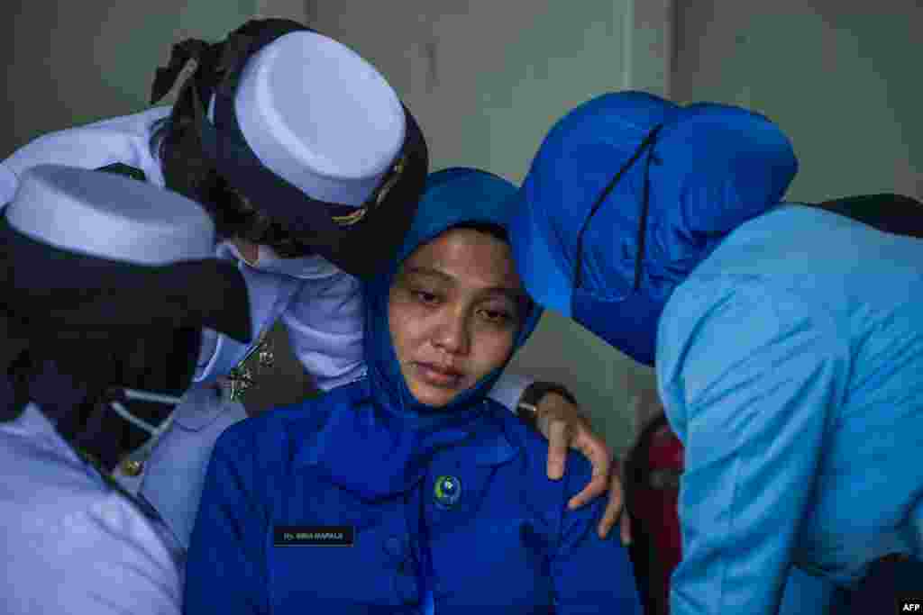Military personnel console a sailor&#39;s wife during a remembrance ceremony for the crew of the Indonesian navy submarine KRI Nanggala that sank on April 21 during a training exercise, on the deck of the hospital ship KRI Dr. Soeharso off the coast of Bali.