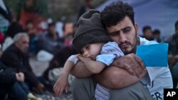 FILE - A Syrian refugee child sleeps on his father's arms while waiting to board a bus, after arriving on a dinghy from the Turkish coast to the northeastern Greek island of Lesbos, Oct. 4 , 2015.