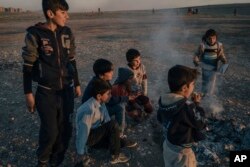 Yazidi children play at sunset outside the Kabarto camp at Duhok, Iraq, for civilians displaced by war in Iraq, Jan. 11, 2017.