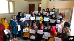 Afghan women chant and hold signs of protest, in Kabul, Dec. 27, 2021. Around 20 members of Afghanistan Women's Political Participation Network protested in a closed area in Kabul while holding signs asking the Taliban for equality.