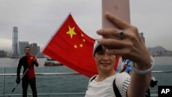 Pro-China supporters take a selfie with a Chinese national flag to support police and anti-violence during a rally at a park in Hong Kong Saturday, Aug. 17, 2019. Another weekend of protests is underway in Hong Kong as Mainland Chinese police are holding drills in nearby Shenzhen