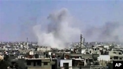 In this image from an amateur video and released by the Syrian Media Council, smoke rises following purported shelling in Homs, Syria, April 10, 2012.
