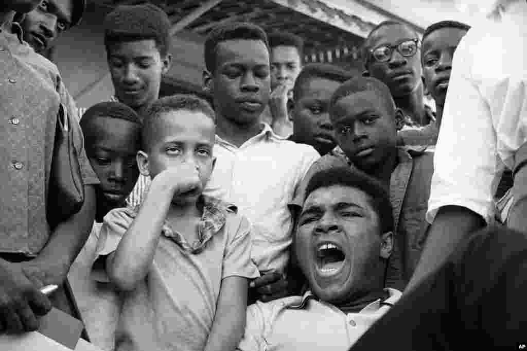FILE - Heavyweight Champion Muhammad Ali exclaims "Why me?" when informed his draft board in Louisville, Ky., had reclassified him 1-A in the draft, Feb. 17, 1966. Ali surrounded himself with youngsters from his neighborhood as he told of his feelings in 