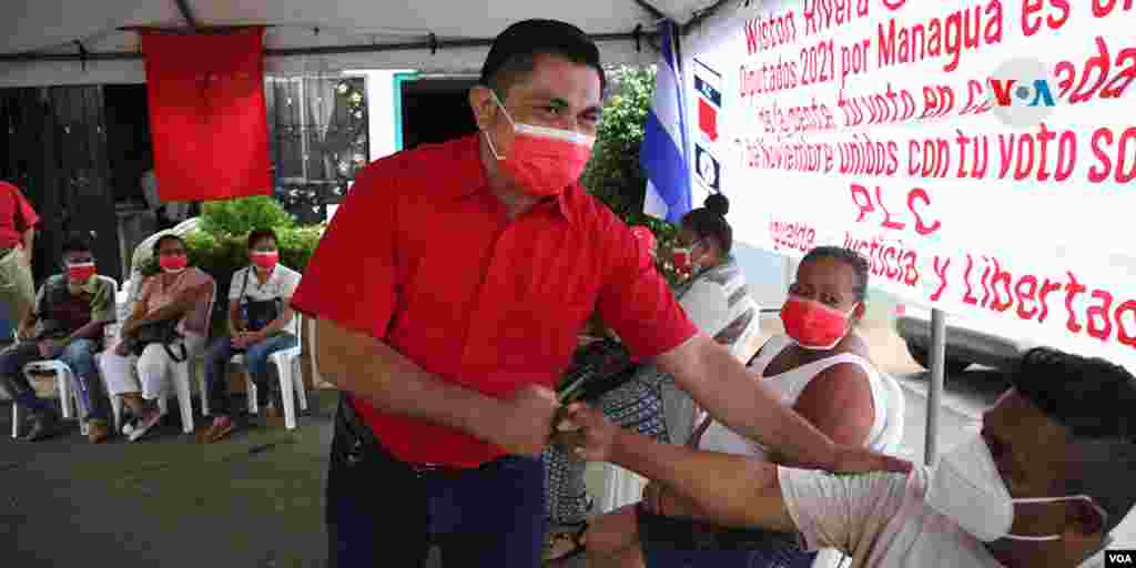 De rojo, Walter Espinoza, candidato presidencial del PLC saluda a sus simpatizantes al llegar a un centro de campaña este jueves.
