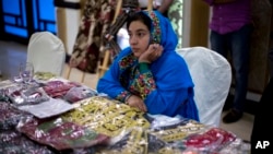 FILE - A refugee from neighboring Afghanistan sells Afghan dresses at a reception organized by the United Nations High Commission for Refugees on the occasion of the World Refugee Day in Islamabad, Pakistan, June 20, 2018.