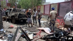 Para pejuang yang setia kepada pemerintah berkumpul di lokasi bom mobil bunuh diri di Aden, Yaman selatan (29/8). (AP/Wael Qubady)