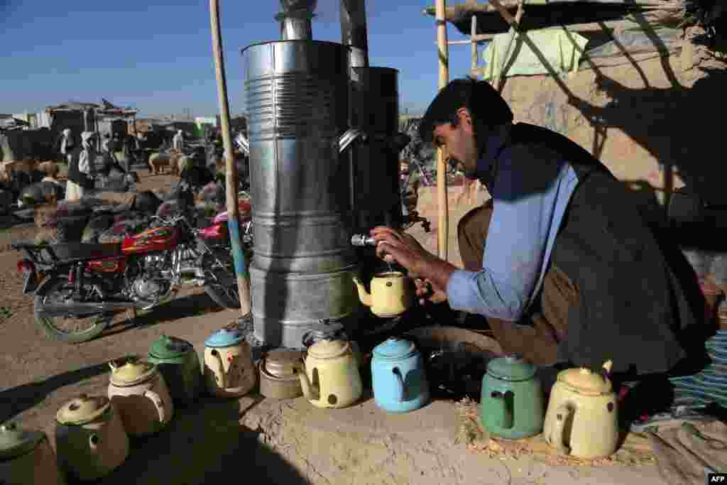 An Afghan man prepares tea for his customers at a livestock market ahead of the sacrificial Eid al-Adha festival in Ghazni. 