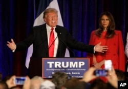 Republican presidential candidate, businessman Donald Trump speaks as his wife, Melania, watches at his caucus night rally in West Des Moines, Iowa, Feb. 1, 2016.