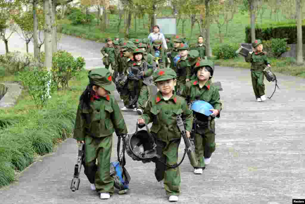 Kindergarten children dressed in military uniforms carry toy guns at a park in Dongyang, Zhejiang province, China.