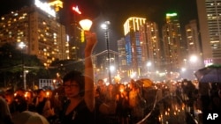 People hold candles under heavy rain as tens of thousands of people attend a candlelight vigil to mark the 24th anniversary of the June 4 Chinese military crackdown on the pro-democracy movement in Beijing, at Victoria Park in Hong Kong, June 4, 2013.