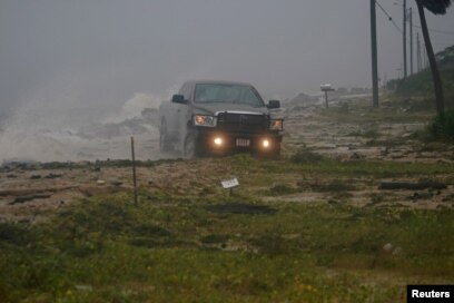 Una camioneta avanza sobre una carretera inundada cuando el huracán Michael avanza por Alligator Point, en Florida. Octubre 10 de 2018. Reuters/Carlo Allegri.