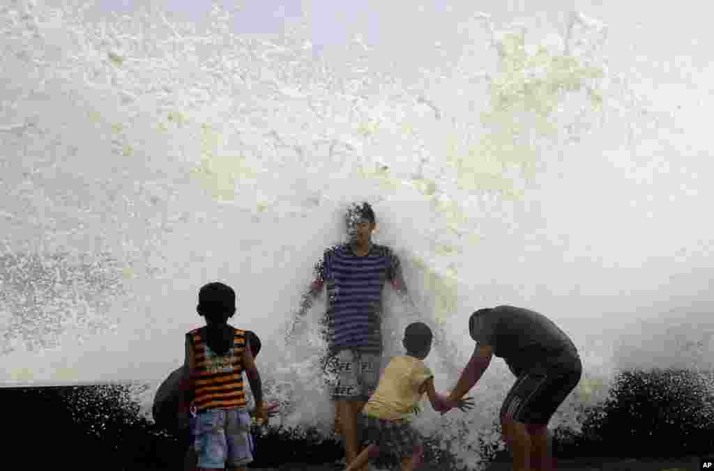 Waves hit the back of a man at the Arabian Sea promenade in Mumbai, India.