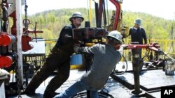 FILE - Workers move a section of well casing into place at a Chesapeake Energy natural gas well site near Burlington, Pa., April 23, 2010.