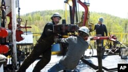 Pekerja memindahkan bagian dari tutup sumur ke tempatnya di lokasi pengeboran gas alam Chesapeake Energy di dekat Burlington, Pennsylvania, 23 April 2010. (Foto: dok).