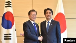 FILE - South Korea's President Moon Jae-in, left, shakes hands with Japan's Prime Minister Shinzo Abe, right, before their meeting at Abe's official residence in Tokyo, Japan, May 9, 2018.
