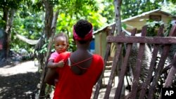 Janila Jean, se yon ti fi 18 tan, ki abite Jakmèl, Ayiti. Li gen yon timoun sou bra li ki se pitit li. Dapre sa Janita di, li te gen 16 zan e li te vyèj lè yon sòlda brezilyen te vyole li nan yon baz militè MINUSTAH. Foto: 15 oktòb, 2016.