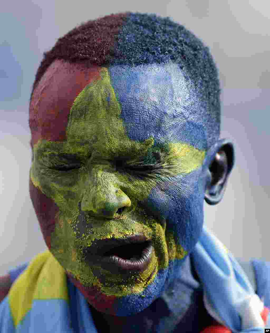 يک هوادار فوتبال اهل جمهوری دمکراتيک کنگو صورت خود را با رنگ های پرچم کشورش آرايش کرده است.