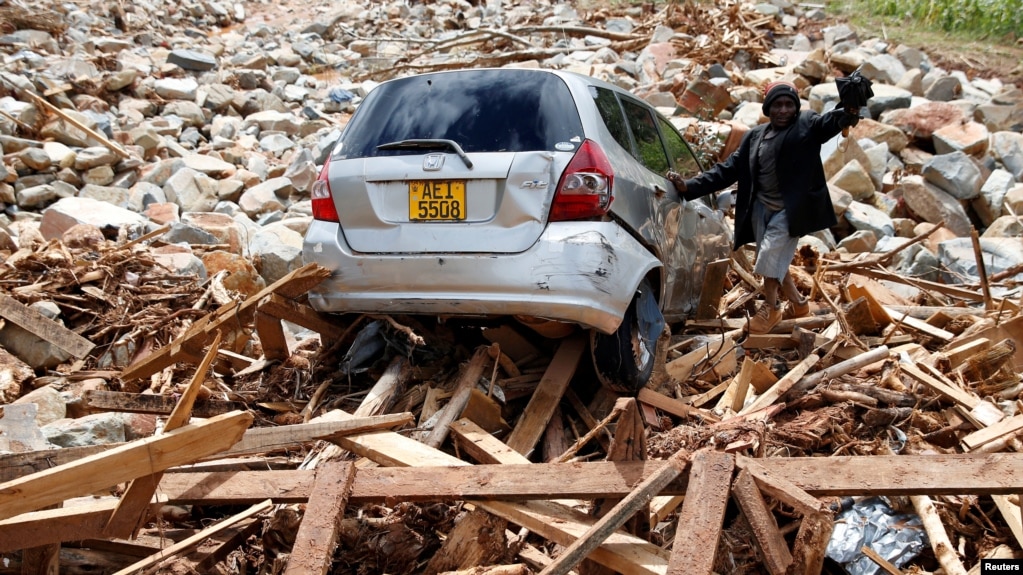 FILE - A man gestures next to his car after it was swept into debris left by Cyclone Idai in Chimanimani, Zimbabwe, March 23, 2019.