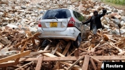 FILE - A man gestures next to his car after it was swept into debris left by Cyclone Idai in Chimanimani, Zimbabwe, March 23, 2019.