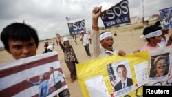 Residents who face eviction from their homes display signs with pictures of U.S. President Barack Obama and Secretary of State Hillary Clinton, as they ask for help in protecting their rights during a protest ahead of their visit in Phnom Penh November 18.