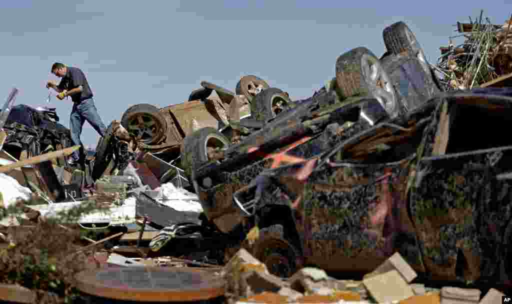 Farmers Insurance worker, Paul Gaipo, looks through tornado-damaged cars at a destroyed strip mall, May 22, 2013, in Moore, Oklahoma.