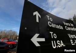 FILE - A sign giving directions is seen in the parking lot of the United States-Canada border in Surrey, British Columbia, Feb. 16, 2017.