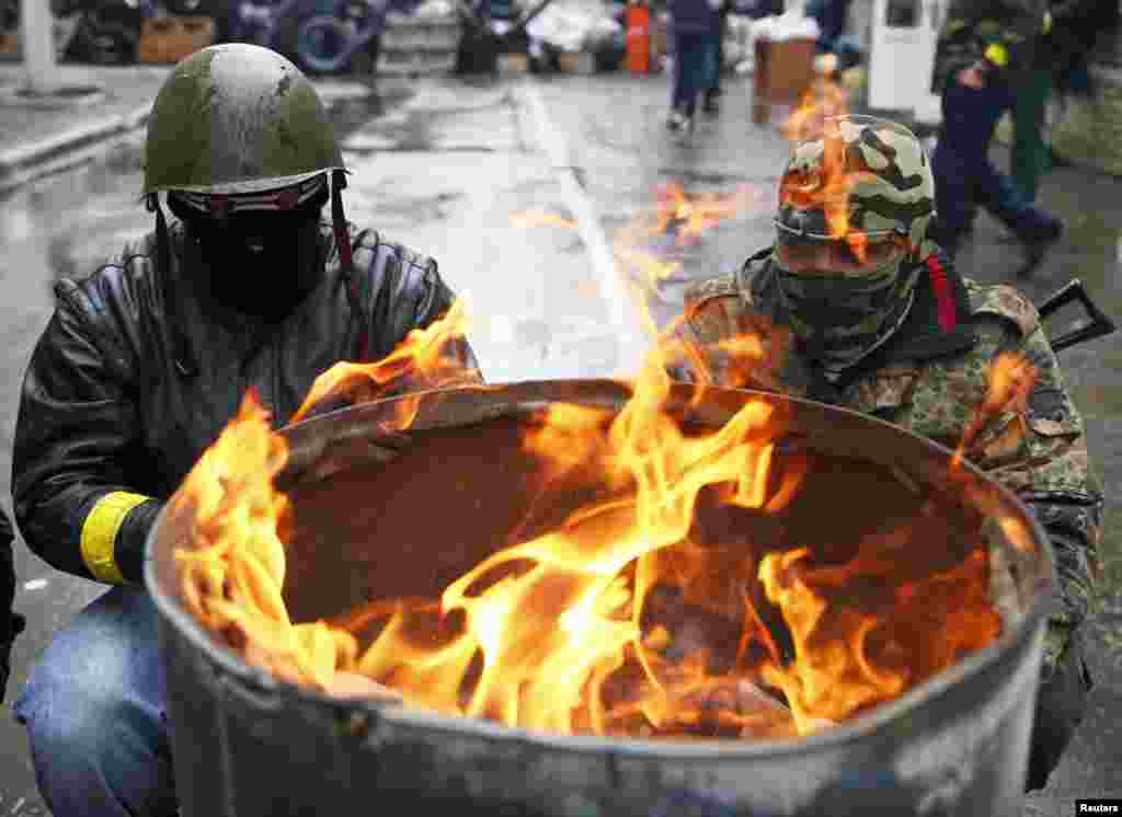 Pro-Russian men gather around a fire at a barricade near the police headquarters in Slovyansk, Ukraine, April 13, 2014.